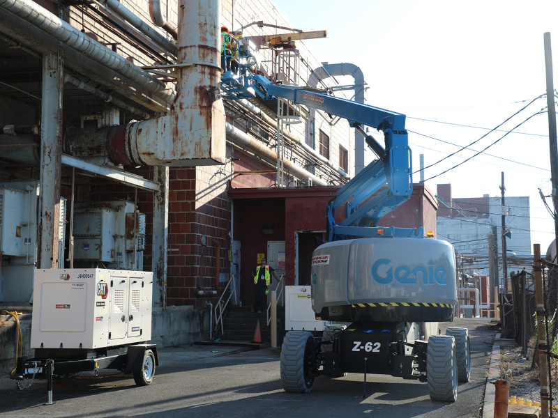 A blue construction crane conducting work on the side of a building