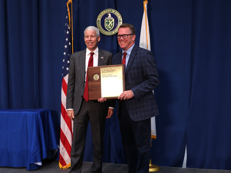 Two professionals holding an award posing for a photo together