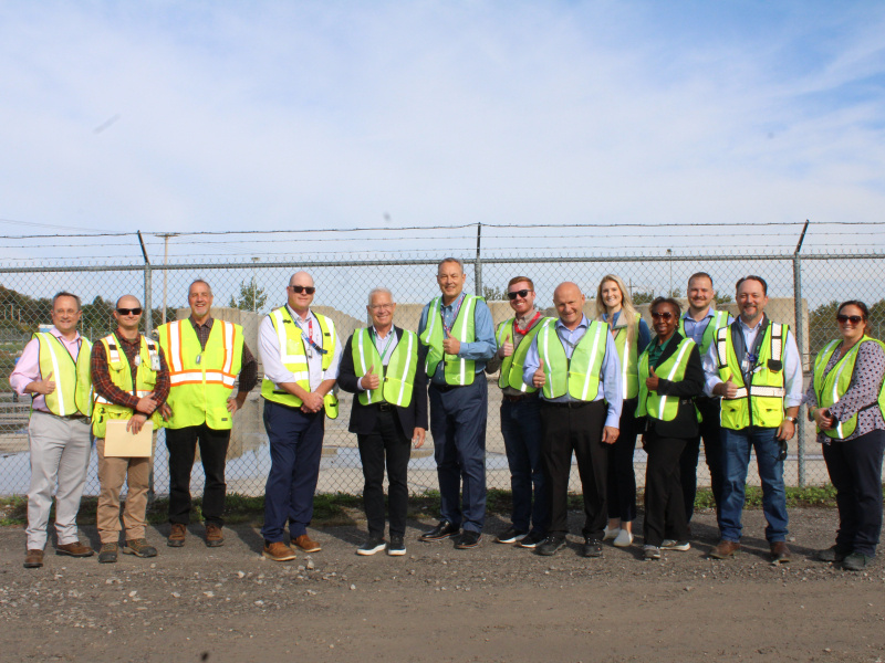 A large group of people in yellow safety vests pose for a photo outside at the West Valley Demonstration Project