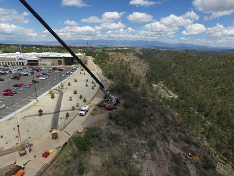 A spider excavator cleans up contaminated soil on a canyonside with Smith’s Marketplace in the background.