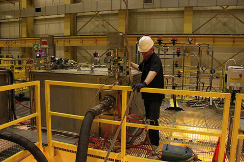 Workers train on a full-scale mockup of sludge removal equipment in a non-hazardous test facility.