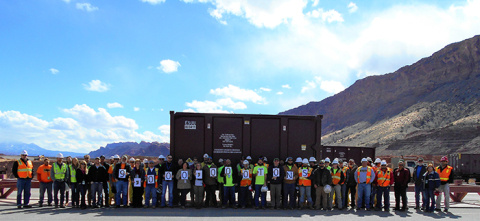 Employees hold signs denoting the milestone of relocating 9 million tons of uranium mill tailings from the Moab Site.