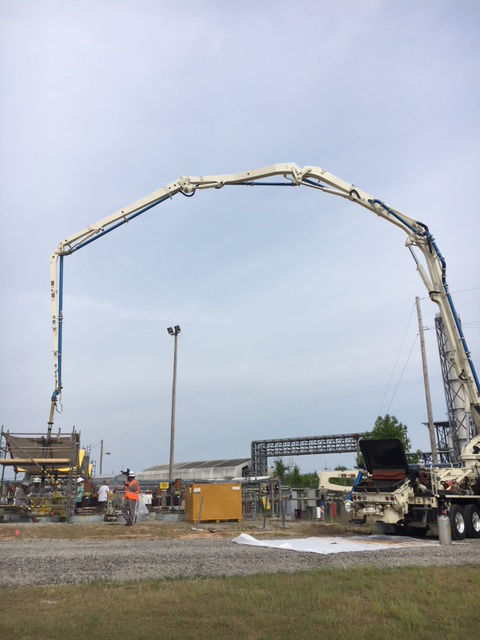An extended boom reaches over the tank farm to pour concrete into the underground storage tanks.