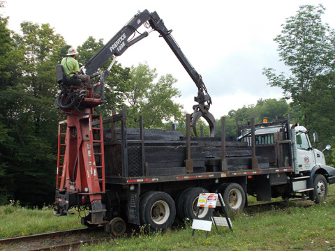 A railroad worker uses a truck-mounted crane to safely place new rail ties along the West Valley Demonstration Project site rail spur tracks to prepare for repairs and straightening.