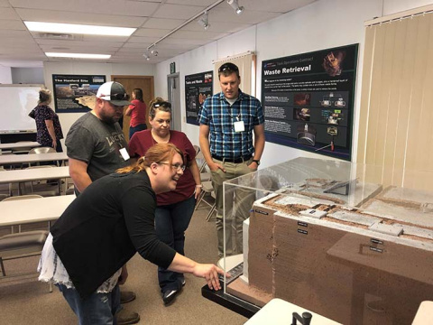 Members of the public view a model of an underground waste storage tank at the Cold Test Facility, one of the stops on this year’s Hanford Site cleanup tour.