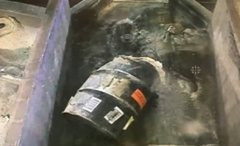 Waste containing roaster oxides is emptied from a drum into a tray at the Accelerated Retrieval Project prior to being raked through with an excavator.
