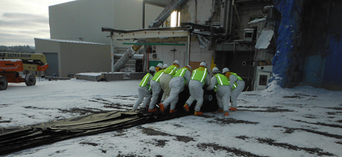 Crew members work together to roll the cover over the Vitrification Facility concrete slab.