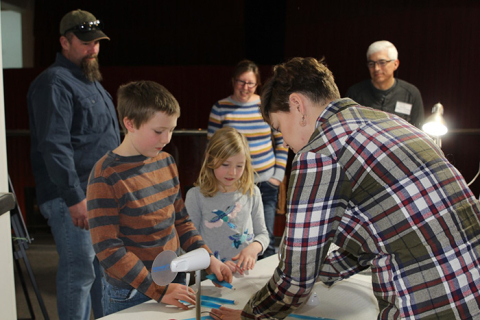 Joseph and Ashley Short watch as Fluor Idaho Mechanical Engineer Elizabeth Bush shows how the pitch of a turbine blade can impact how much electricity is made by a wind turbine.