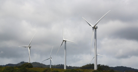 Five wind turbines at varying heights with clouds in the background.