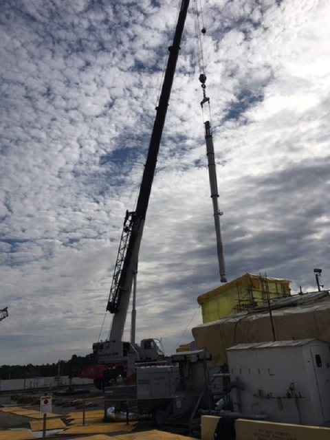 Workers use a crane to move a new pump to a Tank 41 riser for installation.