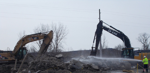Two excavators create efficiencies, with one demolishing the concrete pad for a former facility that treated low-level waste while the other size-reduces and loads debris.