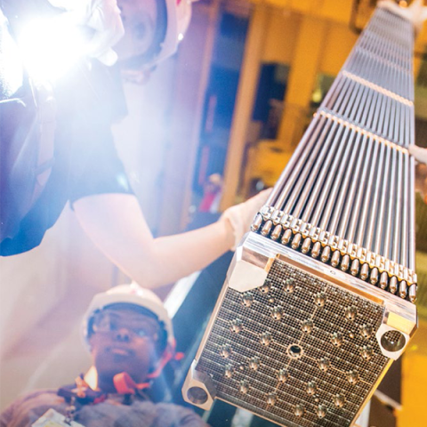 Photo of workers inspecting a fuel assembly.