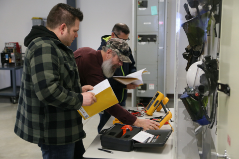 Electrical trainer Gary Lyons, center, leads a hands-on practical exercise for electrical safety training. 