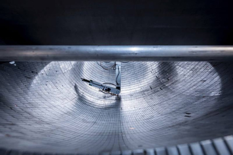 View of the ultracold neutron trap, comprising 5,139 permanent magnets arranged in an asymmetric bowl-shaped array, during magnetic field mapping with a robotic arm.