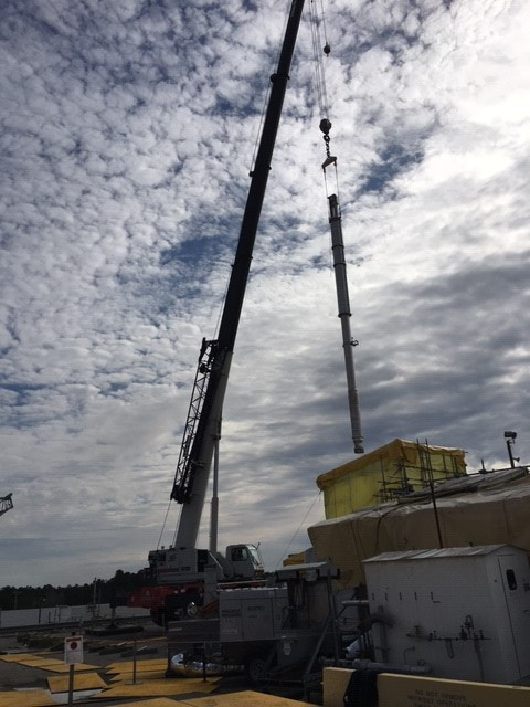 Workers use a crane to move a new pump to a Tank 41 riser for installation.