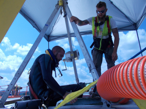 Drew Matteson helps Chris Kunzel safely climb out of the EM West Valley Demonstration Project’s fire water storage tank after Kunzel cleaned its interior walls. The certified divers are with BIDCO Marine Group of Buffalo, New York.