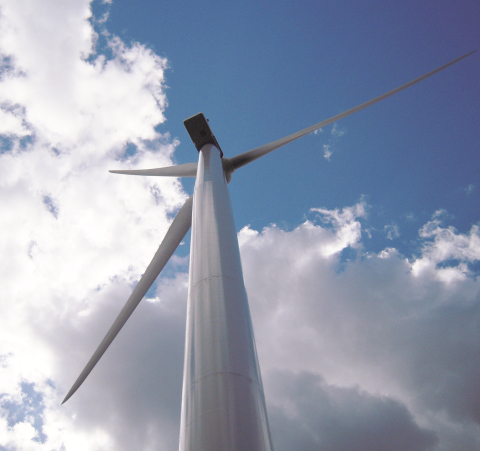 View of a wind turbine from below against a blue sky.