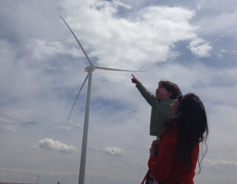A NREL employee's daughter points at the turbines while in her mother's arms at the National Wind Technology Center.