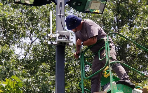 Photo of a man in a bucket truck looking at outdoor lighting controls.