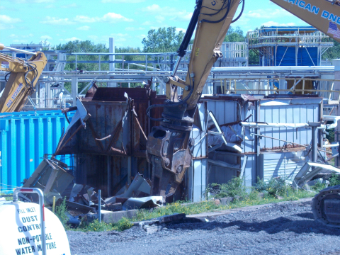 An operator uses a hydraulic shear to remove one of two Waste Tank Farm condenser structures at the West Valley Demonstration Project. 