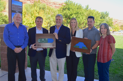 Officials hold plaques representing the Moab Uranium Mill Tailings Remedial Action (UMTRA) Project’s progress moving waste to a permanent disposal cell. 