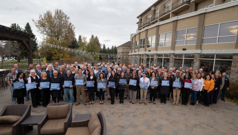 Participants in DOE's recent safety culture workshop in Idaho Falls gather for a photo, with some attendees holding safety messages.