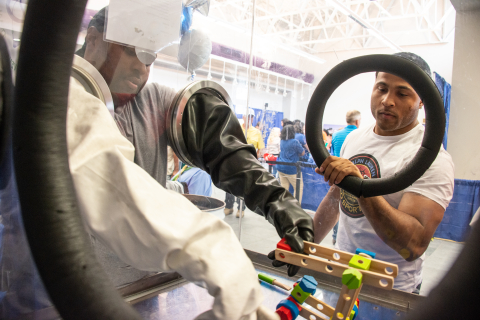 Savannah River Site Safety Expo attendees take part in demonstrations, such as maneuvering objects in a glovebox.