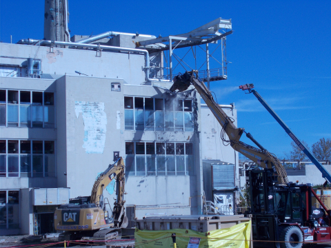 A large excavator takes the first bite out of the former Main Plant Office Building at EM's West Valley Demonstration Project site.