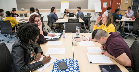 Four students share ideas as they work together to design a wall retrofit product as part of NREL’s mini-hackathon challenge.