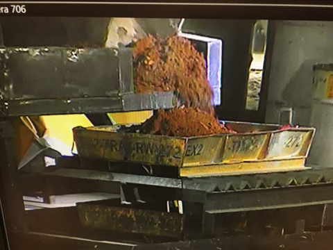 An excavator empties the contents of a sludge drum into a sorting tray at the Accelerated Retrieval Project VII facility. 
