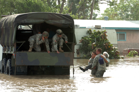 Military personnel rescuing residents from a flooded area