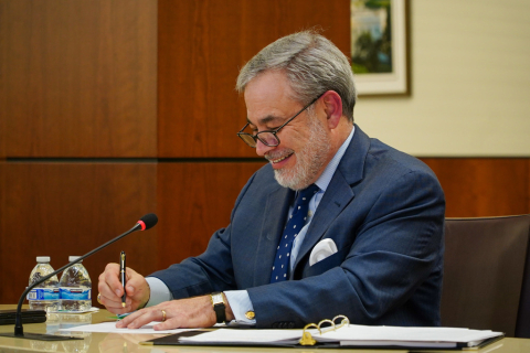 Secretary Brouillette smiles while signing a document