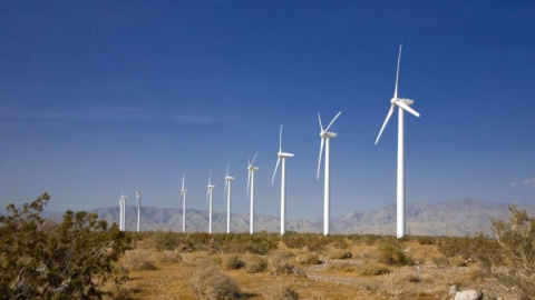 Wind turbines in an arid environment contrasted against a stark blue sky