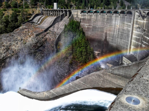 Photograph of Diablo Dam with a rainbow shining off of the flowing water. 