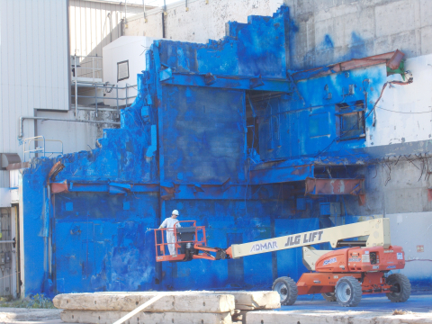 A worker at the West Valley Demonstration Project applies a fixative to the concrete slab of the former Main Plant Office Building to protect employees from potential asbestos.