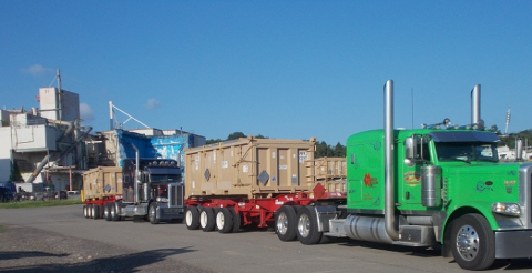 Trucks carrying waste containers leave the West Valley Demonstration Project in late July en route to an offsite disposal facility. Pictured in the background is the Main Plant Process Building, which is set for demolition this year.