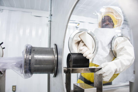 Operator Charlie Stokes uses a specialized cart to move material through a glovebox mock-up as part of training activities for resuming work in the K Area Interim Surveillance glovebox at the Savannah River Site following completion of a process optimizat