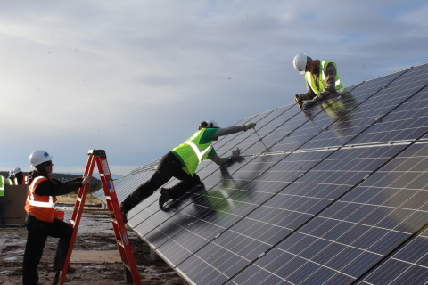 Three workers installing on some solar panels.