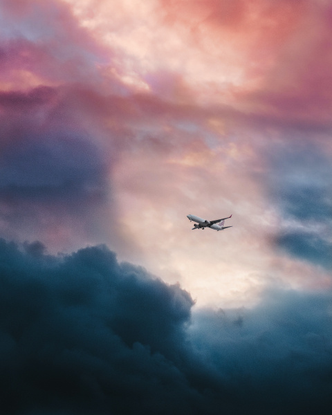 White plane flying through clouds. 