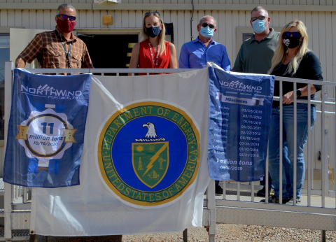 Officials with the Moab Uranium Mill Tailings Remediation Action Project hold up commemorative flags recognizing the milestone of disposing 11 million tons of mill tailings. 