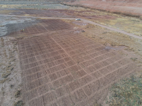 Moab Uranium Mill Tailings Remedial Action Project Environment Technician Luke Mattson and Project Engineer Chris Pulskamp, shown in the upper left corner of the photo, examine revegetation test plots after the land was prepped for planting.