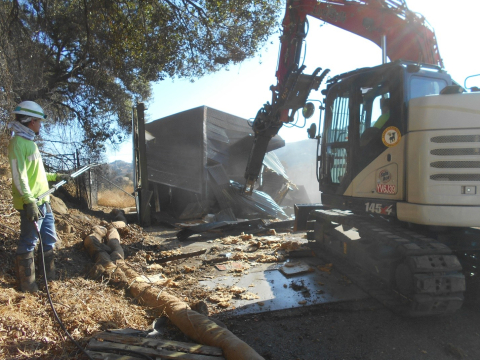 Jayme Gillen, an employee with North Wind Portage, EM's cleanup contractor at the former Energy Technology Engineering Center site, sprays water to mitigate dust while crews demolish one of eight DOE-owned buildings remaining at the site.