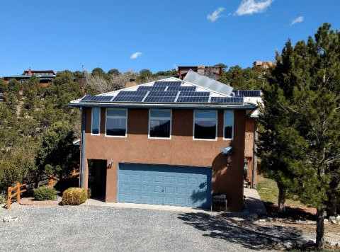 “Wayne’s World” from the south side. The was taken in the late morning on the equinox. The sun barely makes it to the bottom of the windows, so there will be no direct solar gain on the south side from April to October. The one large roof panel is a solar hot water panel, and the rest are solar electric.  The thin windows on the side of the building allow the sun to heat the thermal walls.