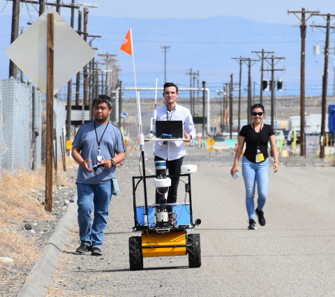 During a recent road closure on the Hanford Site, Florida International University students, from left, Jeff Natividad, Joel Adams, and Thi Tran, test a radiation mapping robot outside a tank farm. The students are part of a unique internship program between EM and the university.