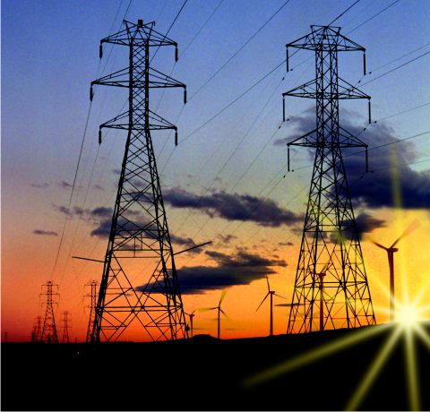 Large electrical grid towers stand alongside wind turbines, with the sun setting behind them.