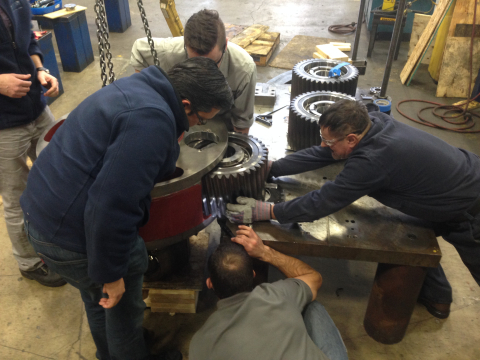 Four engineers work to assemble a wind turbine gearbox.