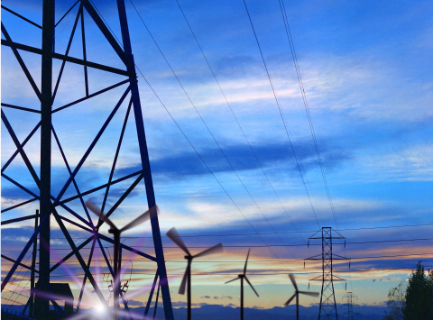 Wind turbines and grid towers against the sunset.