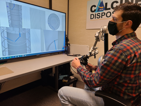 Idaho National Laboratory Site Calcine Retrieval Project Design Engineer Derek Allen tests a robotic arm and related software that uses haptic feedback in advance of full-scale testing.