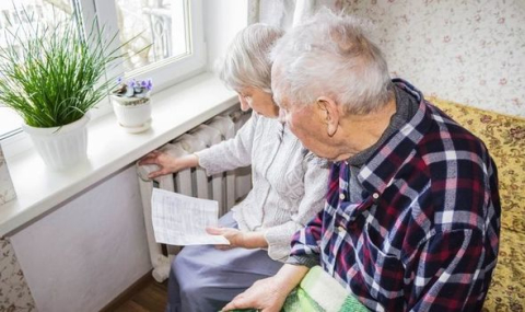 Elderly couple reading energy bill by the radiator