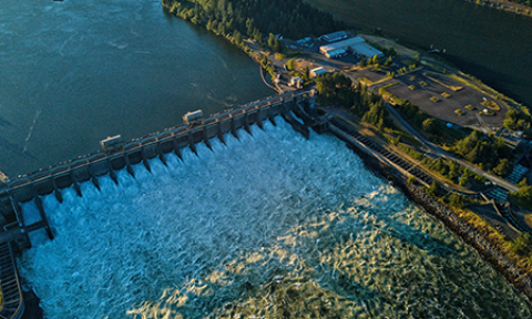 An aerial view of a small dam on one branch of a river that splits in two.